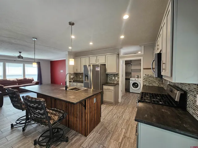 a kitchen with stainless steel appliances granite countertop a stove top oven a sink dishwasher a dining table and chairs with wooden floor