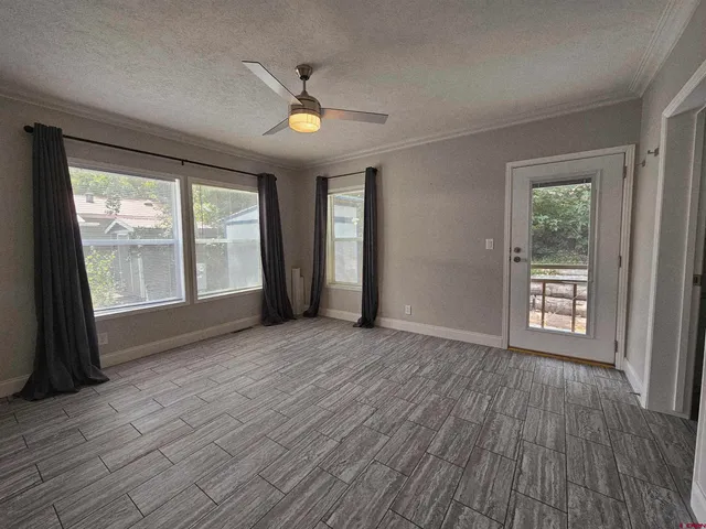 an empty room with wooden floor and windows