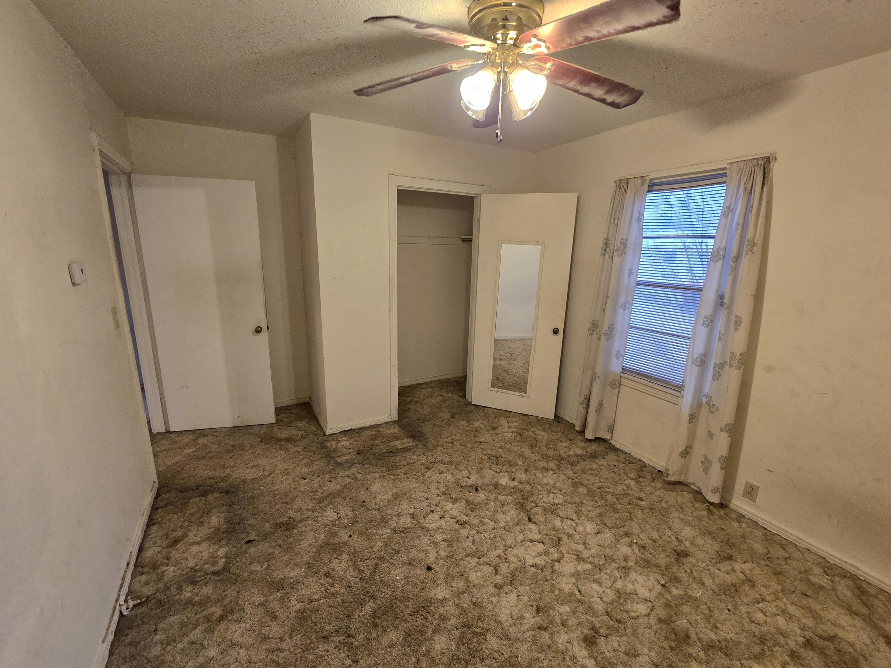 807 Northwest 8th Street Seminole, TX 79360 - Photo 9 of 15 an empty room with closet and a chandelier fan