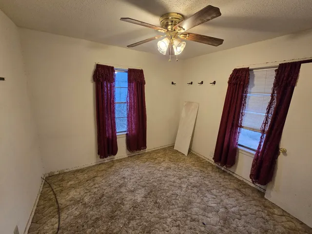 a view of a room with a chandelier fan and wooden floor
