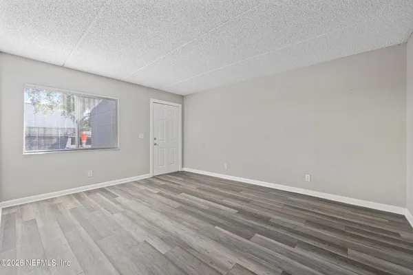 a view of an empty room with wooden floor and a window
