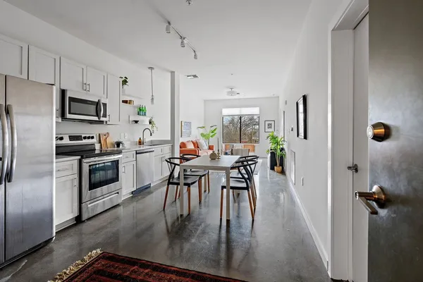 a kitchen with stainless steel appliances a table chairs refrigerator and microwave