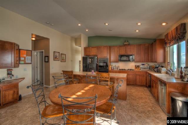 a kitchen with stainless steel appliances kitchen island granite countertop a sink refrigerator and cabinets