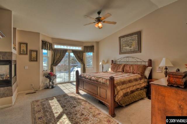 940 Flanders Road Reno, NV 89511 - Photo 5 of 9 a spacious bedroom with a bed a couch and a chandelier