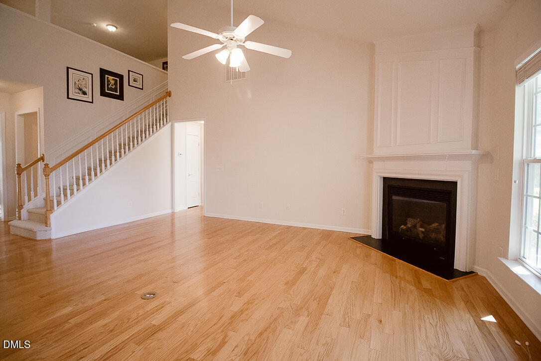 5335 Brandy Bay Road Raleigh, NC 27613 - Photo 7 of 29 a view of an empty room with wooden floor and a fireplace