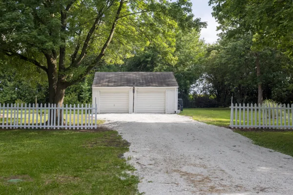 a front view of a house with a garden and trees