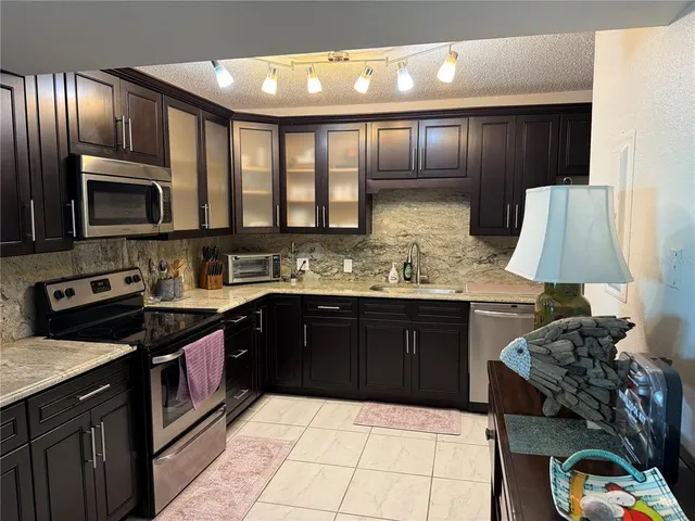 a kitchen with stainless steel appliances granite countertop wooden cabinets a stove top oven and a granite counter top