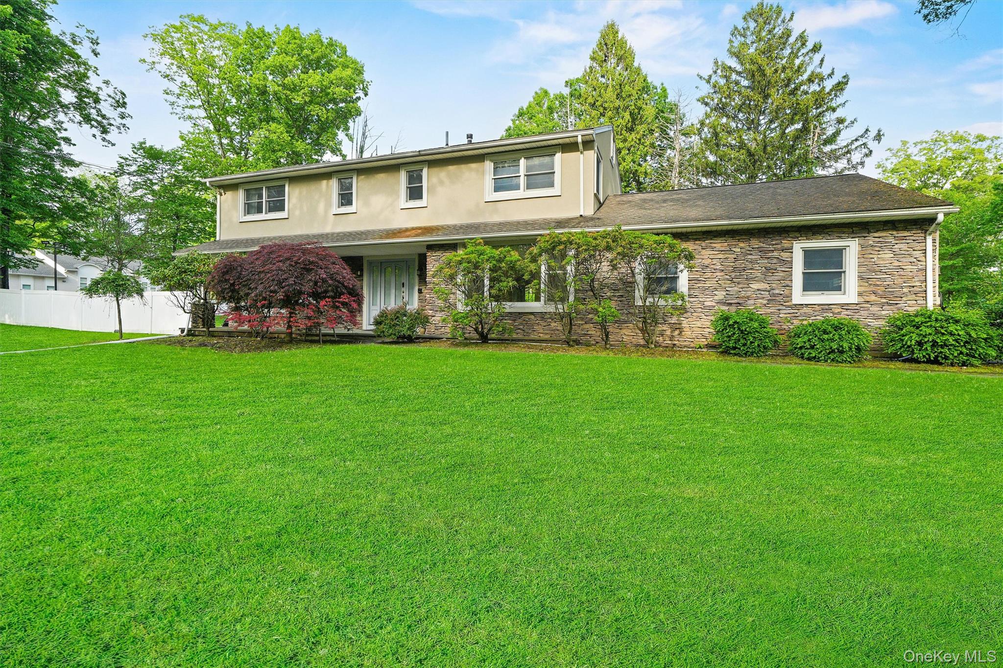 Traditional-style home with stone siding, stucco siding, covered porch, and a shingled roof