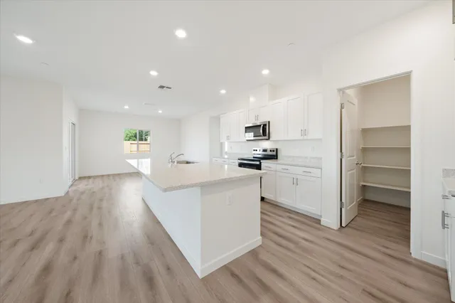 a kitchen with granite countertop a sink a stove top oven a counter space and cabinets