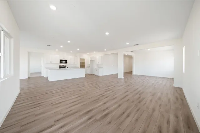 a view of empty room with wooden floor and kitchen view