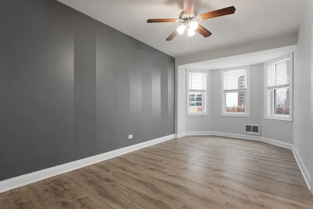 a view of an empty room with window and wooden floor