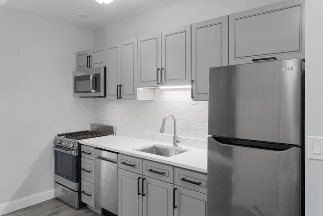 a kitchen with stainless steel appliances granite countertop a refrigerator a sink and white cabinets