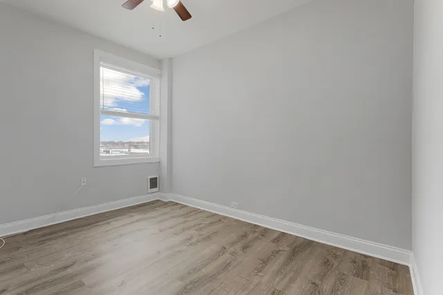 an empty room with a window and a ceiling fan