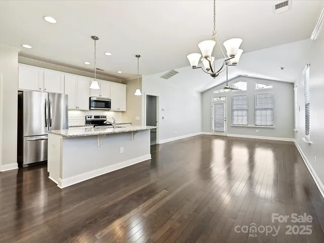 a view of a kitchen with a stove a microwave and wooden floor