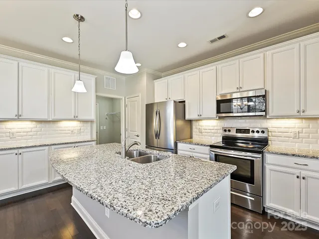 a kitchen with stainless steel appliances granite countertop a sink stove and refrigerator
