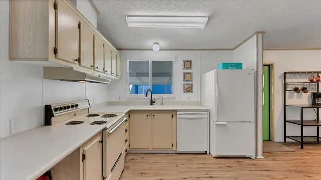 a kitchen with stainless steel appliances a refrigerator a sink a stove and white cabinets with wooden floor