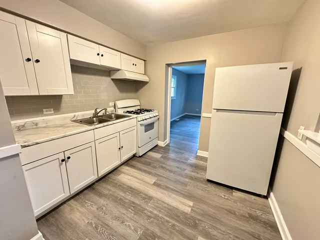 a kitchen with sink a refrigerator and white cabinets