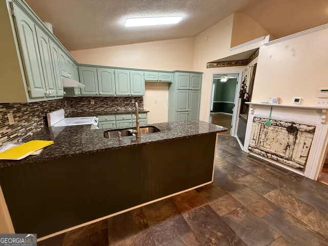 a kitchen with granite countertop a refrigerator a stove and a sink