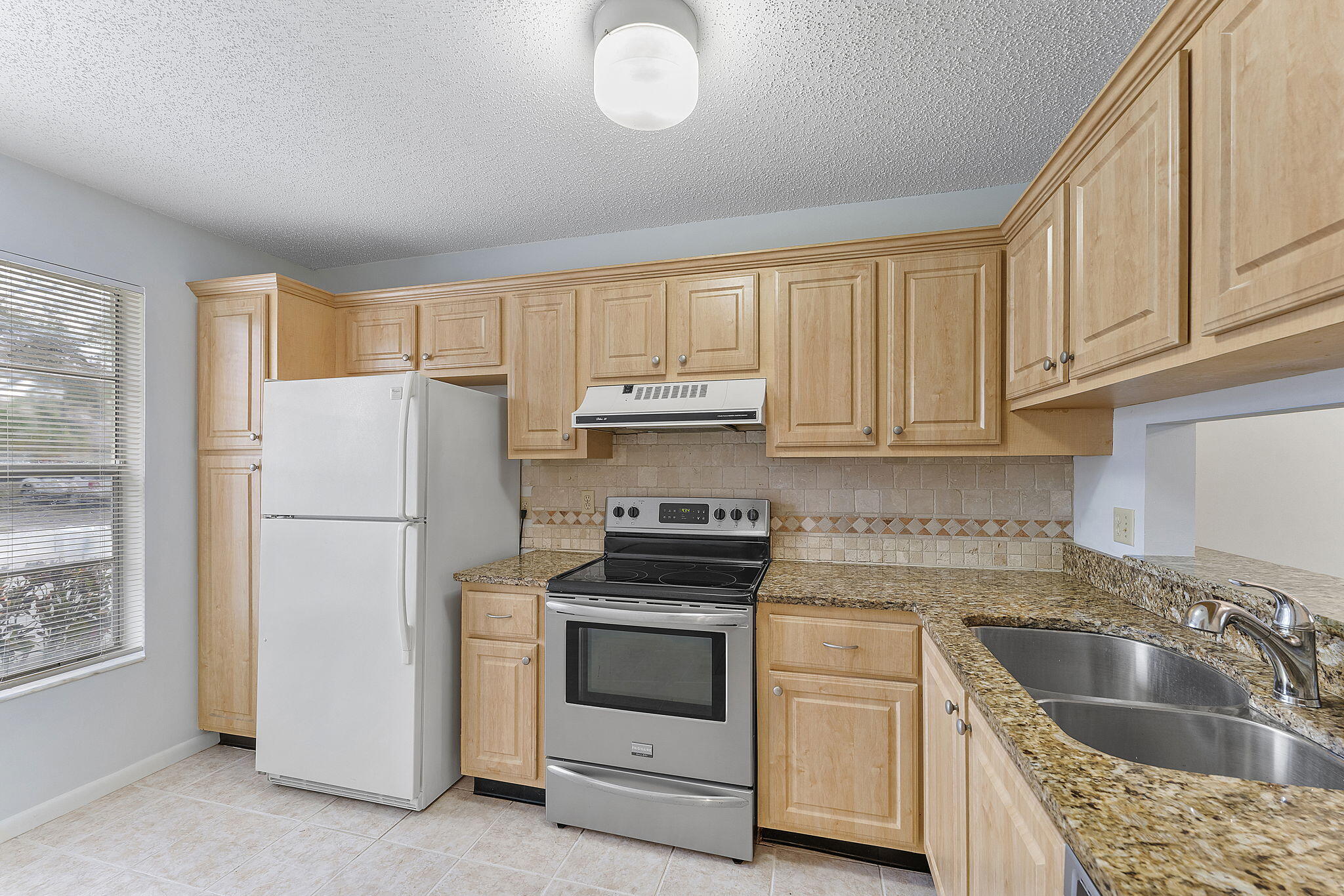 115 Oakwood Drive Jupiter, FL 33458 - Photo 3 of 21 a kitchen with granite countertop white cabinets and white appliances