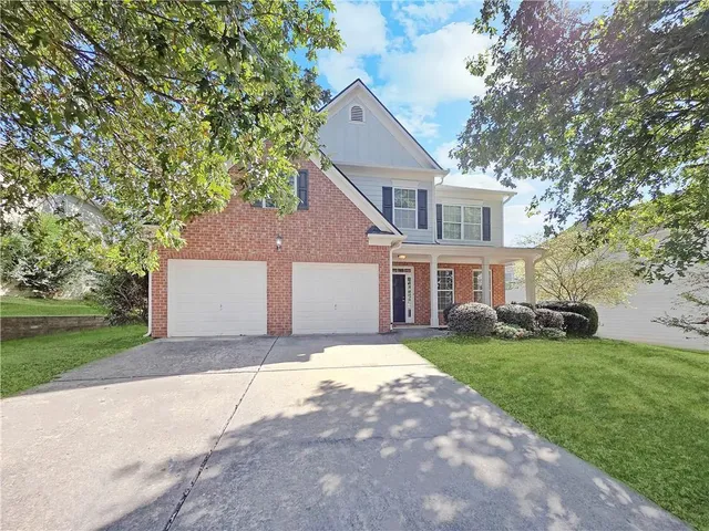 a front view of a house with a garden and trees