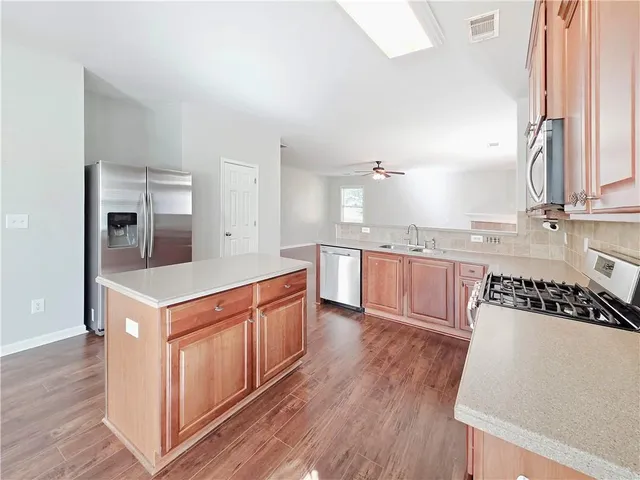 a kitchen with stainless steel appliances granite countertop a white cabinets and wooden floors
