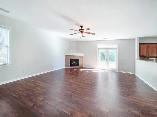 an empty room with wooden floor fireplace and windows