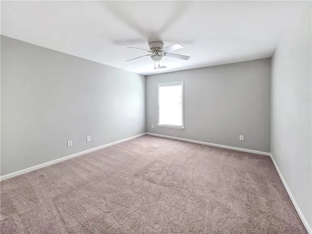 an empty room with a window and a ceiling fan