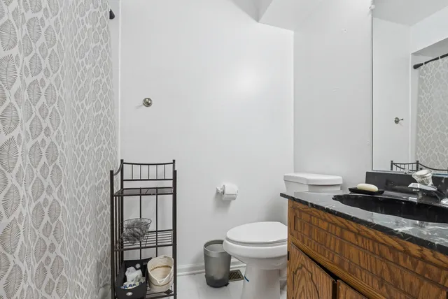a bathroom with a granite countertop sink and a toilet