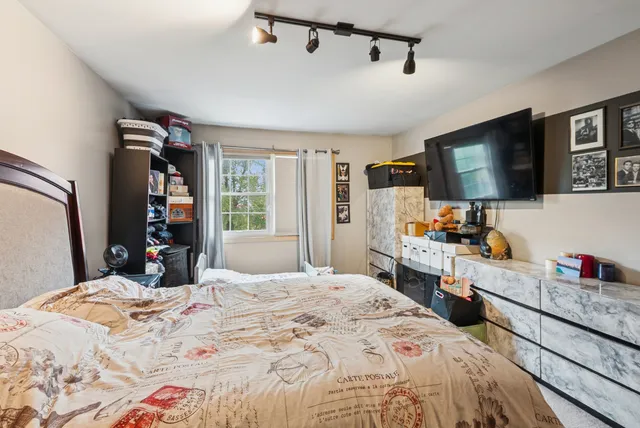 a bedroom with a bed and a flat tv screen on dresser