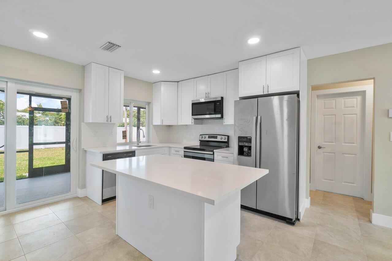 245 Southwest 6th Street Boca Raton, FL 33432 - Photo 7 of 40 a kitchen with stainless steel appliances a refrigerator stove microwave and sink