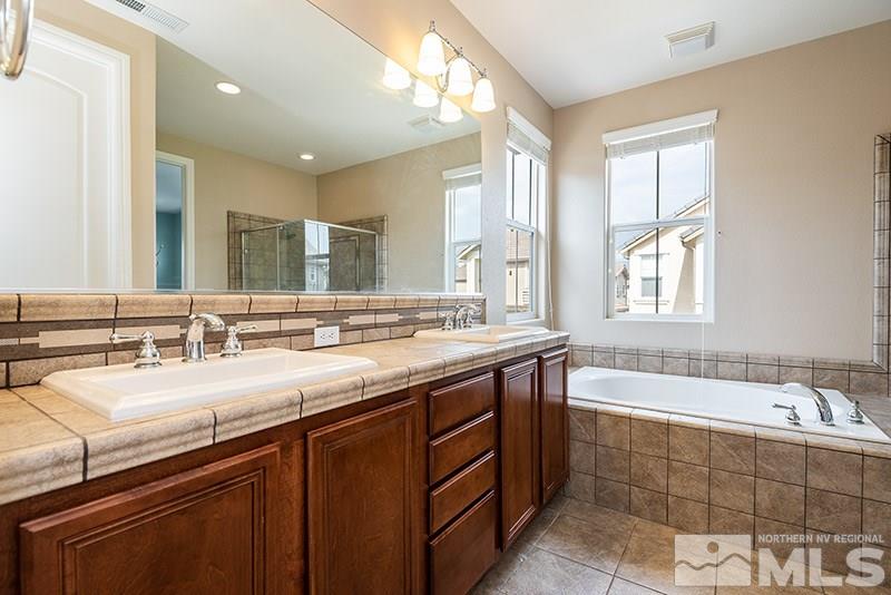 7677 Stone Bluff Way Reno, NV 89523 - Photo 8 of 17 a bathroom with a bathtub a double vanity sink and mirror