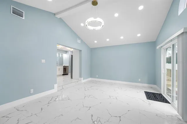 a view of an empty room and a kitchen with electric equipment