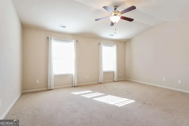 an empty room with fan and windows
