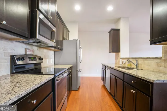a kitchen with stainless steel appliances granite countertop a sink a stove and a wooden floors