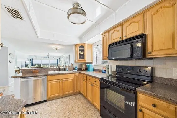 a kitchen with stainless steel appliances granite countertop a sink a stove a refrigerator cabinets and a dining table