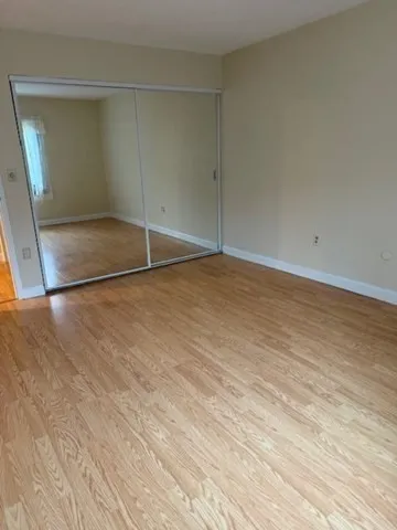 an empty room with wooden floor and mirror