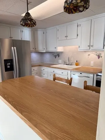 a kitchen with stainless steel appliances a refrigerator a stove a sink and white cabinets