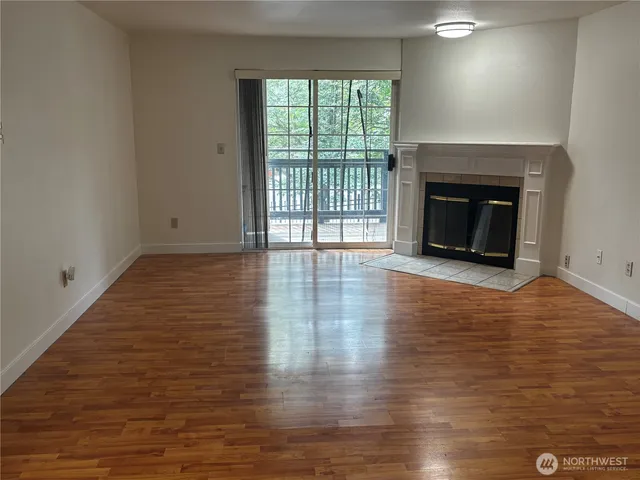 a view of a livingroom with wooden floor and a fireplace