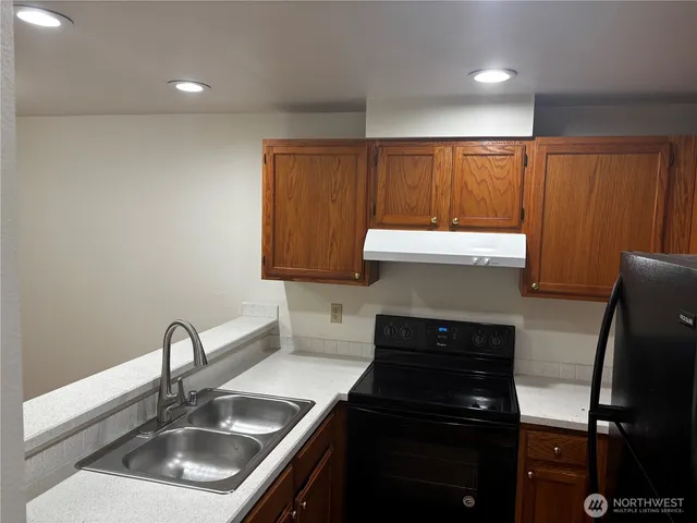 a kitchen with a sink and a stove top oven with wooden floor