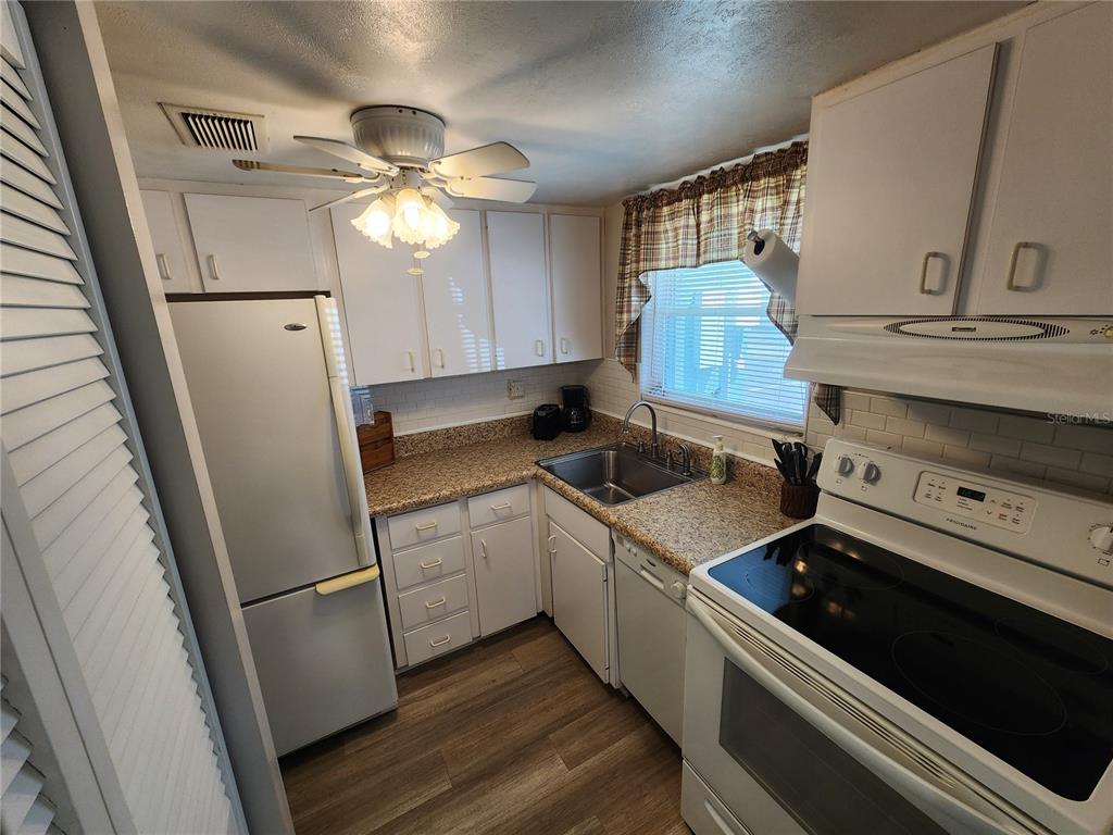5842 Welcome Road, Unit J2 Bradenton, FL 34207 - Photo 13 of 25 a kitchen with a stove and white cabinets