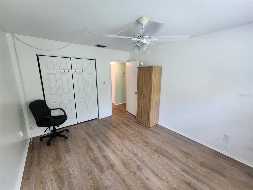 5842 Welcome Road, Unit J2 Bradenton, FL 34207 - Photo 21 of 25 an empty room with wooden floor fan and windows