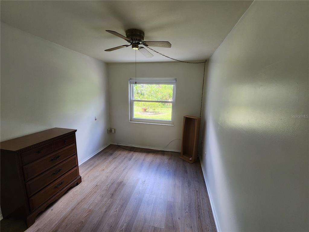 5842 Welcome Road, Unit J2 Bradenton, FL 34207 - Photo 22 of 25 an empty room with wooden floor fan and windows