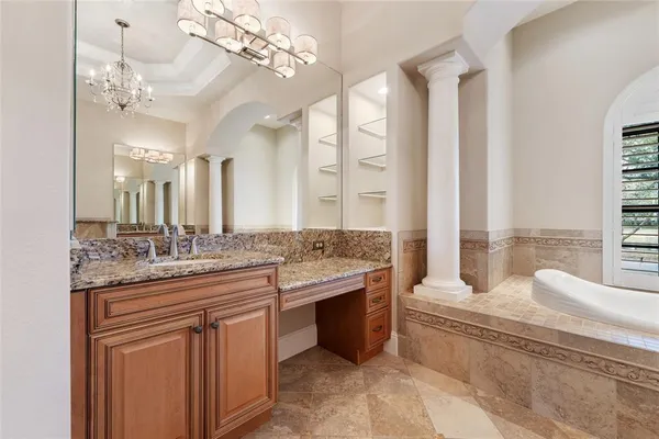 a bathroom with a granite countertop sink a large mirror and a bathtub next to a window