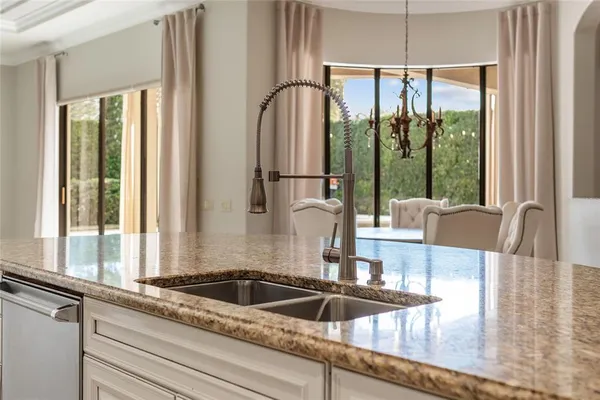 a kitchen with a sink a counter top space and a view of living room