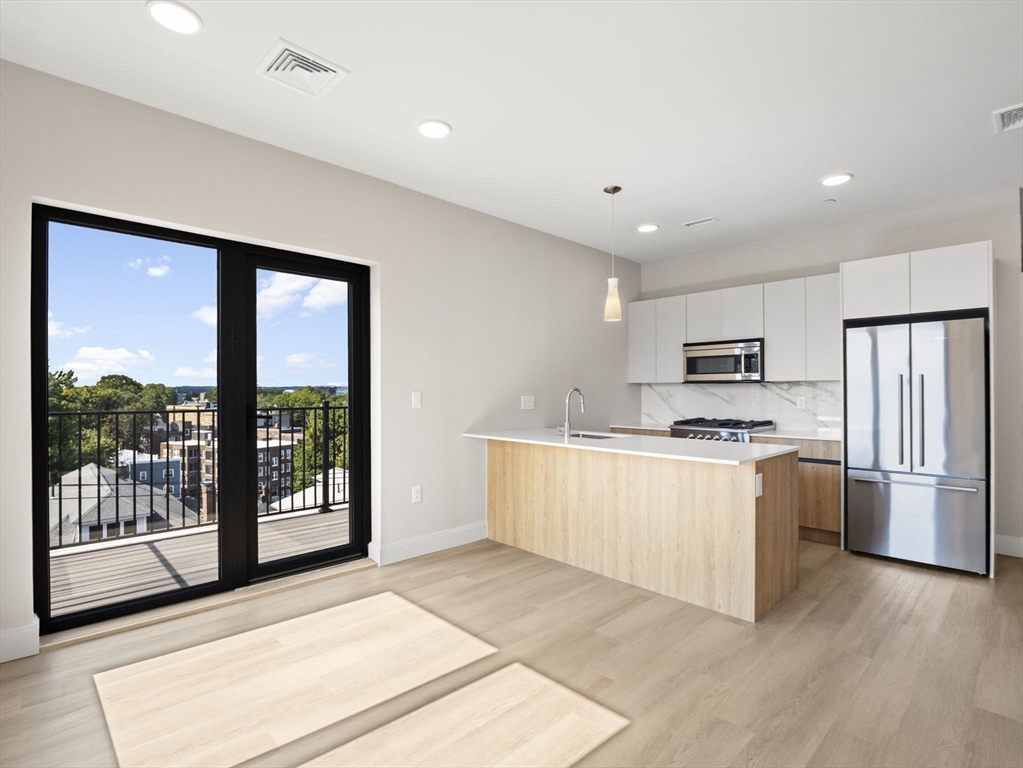 249 Corey Road, Unit 401 Boston, MA 02135 - Photo 2 of 34 a kitchen with stainless steel appliances granite countertop a stove top oven a refrigerator a sink and a dishwasher with wooden floor