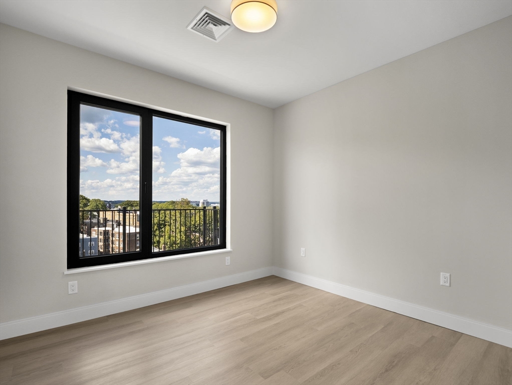 249 Corey Road, Unit 401 Boston, MA 02135 - Photo 10 of 34 wooden floor in an empty room with a window