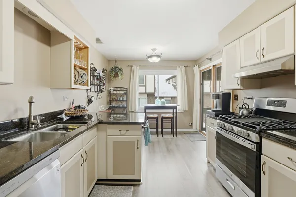 a kitchen with granite countertop a sink cabinets stainless steel appliances and a window