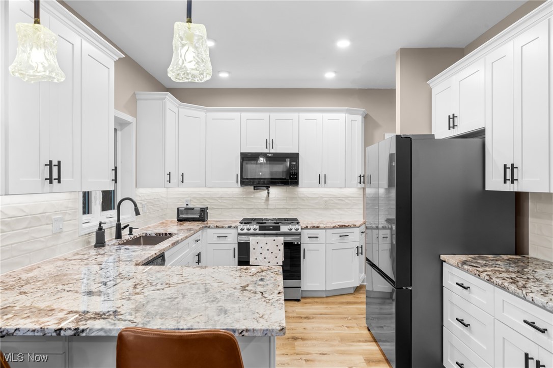 39600 Aurora Road Solon, OH 44139 - Photo 15 of 49 Kitchen featuring appliances with stainless steel finishes, white cabinets, light stone counters, and recessed lighting
