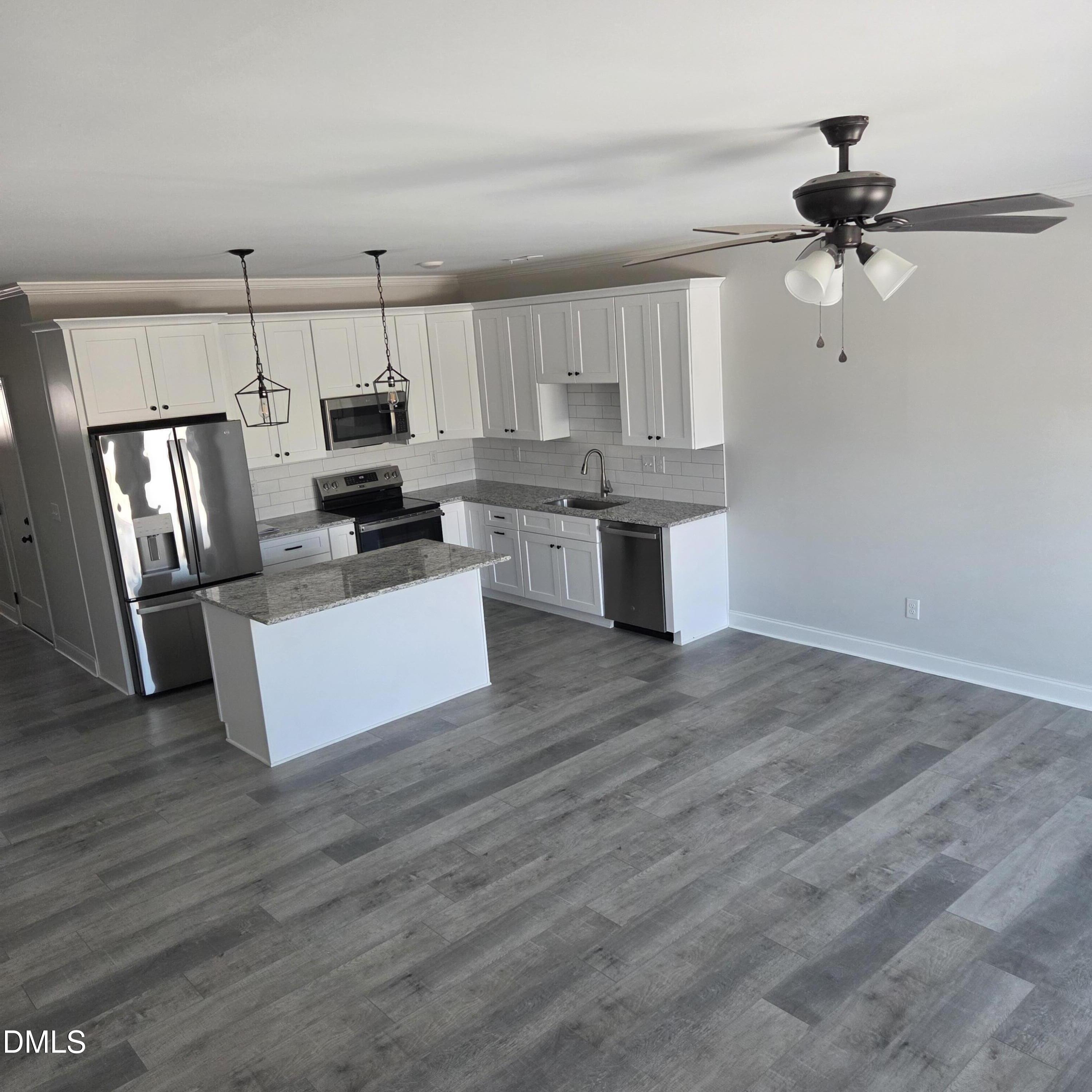249 North Hickory Street Angier, NC 27501 - Photo 3 of 4 a kitchen with kitchen island granite countertop a stove top oven a sink dishwasher a refrigerator and white cabinets with wooden floor