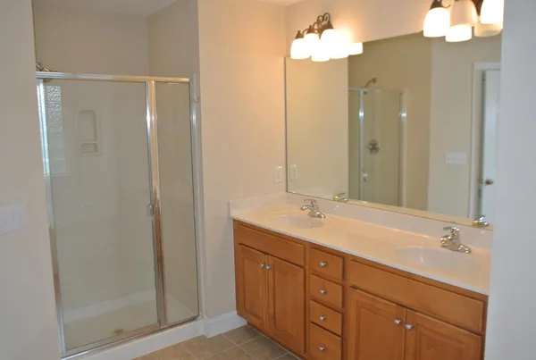 a bathroom with a double vanity sink and mirror with shower
